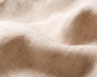 Close-up of light beige linen suit fabric with visible natural texture and weave pattern