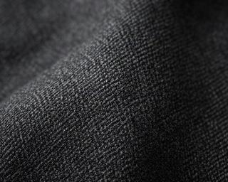 Dark wool suit fabric in close-up showing the dense twill weave and rich charcoal color